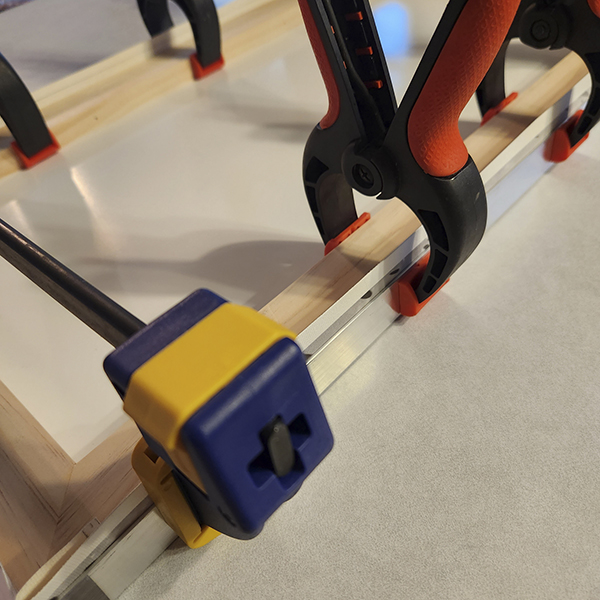 Clamps and angle iron are used to position the canvas onto the cradle